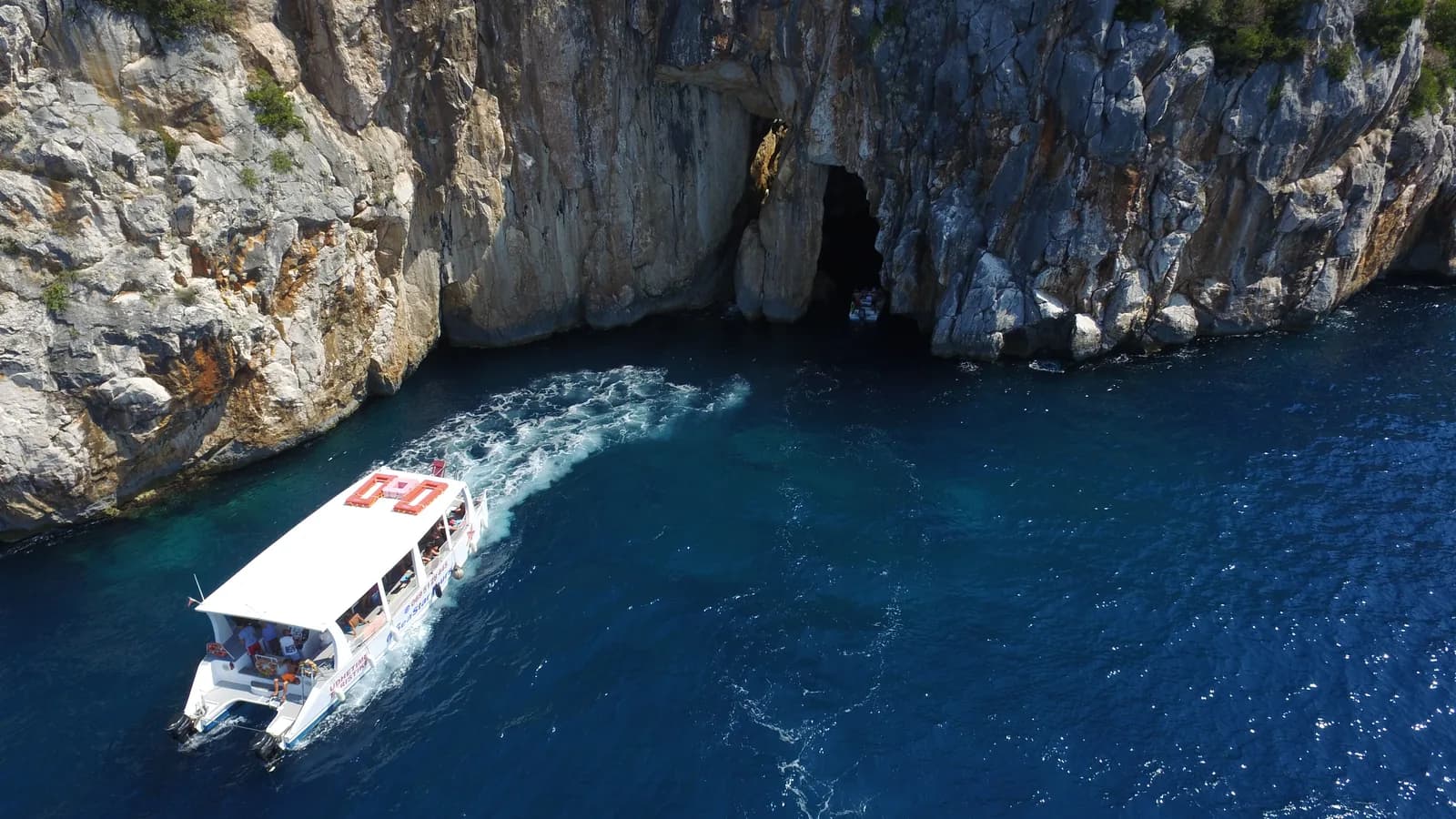 White boat entering a deep blue sea cave on the Albanian Riviera with Riviera Boats AL