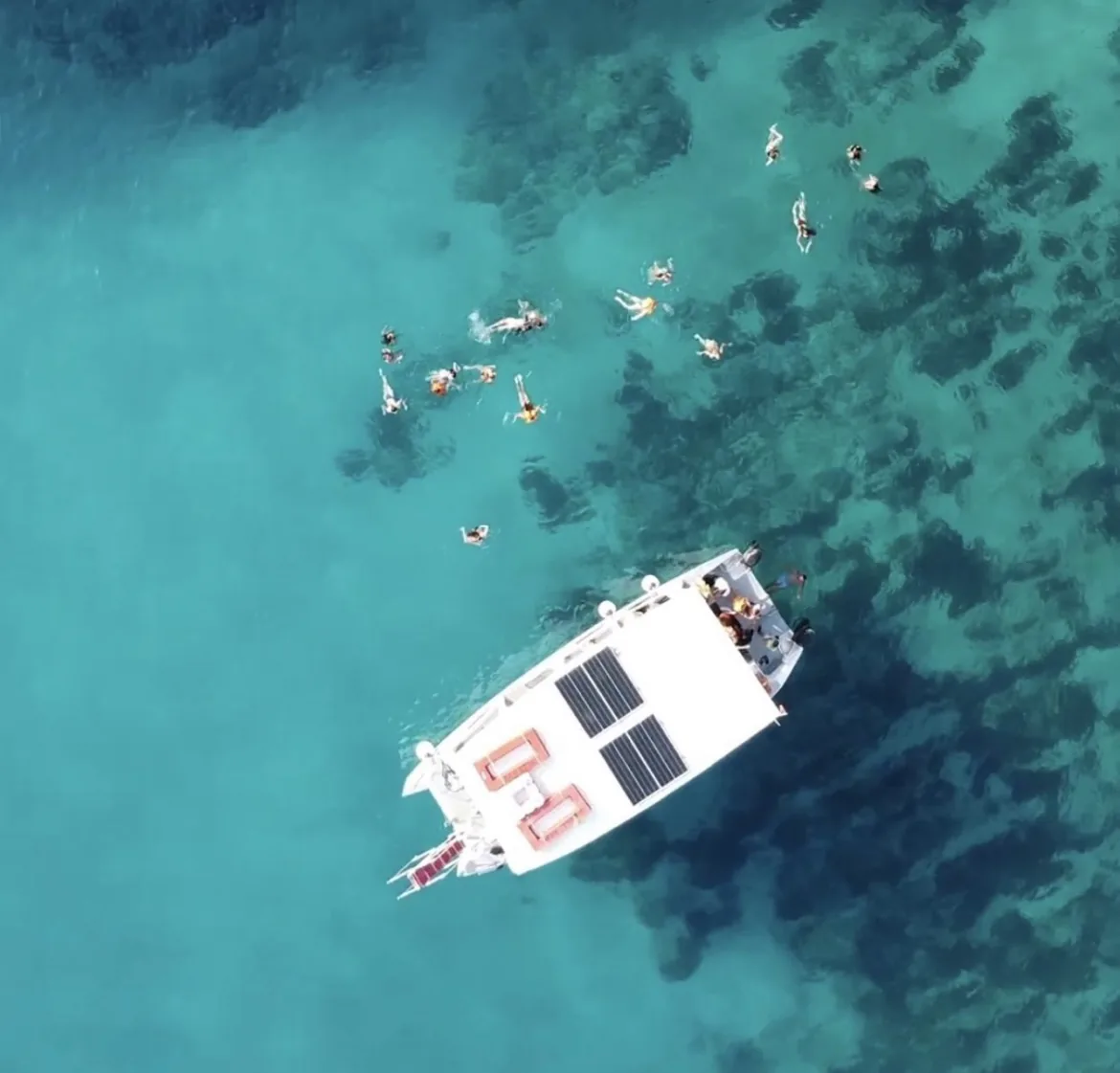 Aerial view of swimmers around a Riviera Boats AL boat in turquoise Ionian water